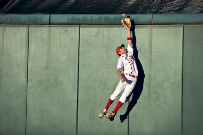 A baseball player jumping to catch a ball