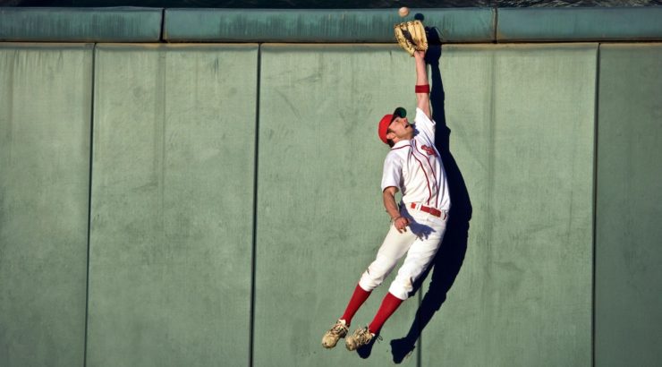 A baseball player jumping to catch a ball